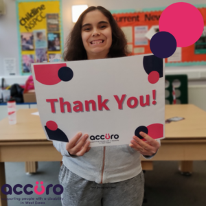 Loughton Youth Group Member smiling as she holds up a large sign reading 'thank you!'