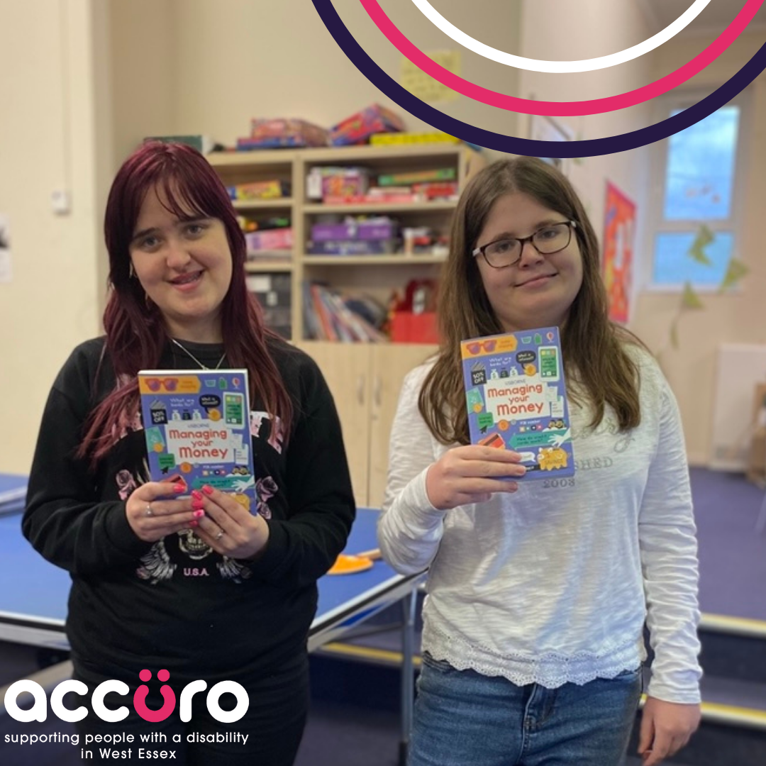 Two STRIDE members smiling and holding 'managing your money' booklets