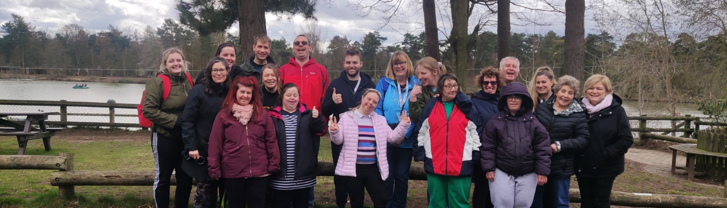 Group photo of Adult Friendship Scheme members and staff in front of a lake at Center Parcs in 2023.